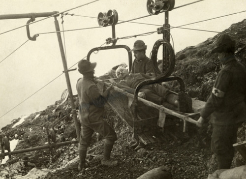 Italian Alpine soldiers and medic transporting a wounded soldier between mountains by cable stretche