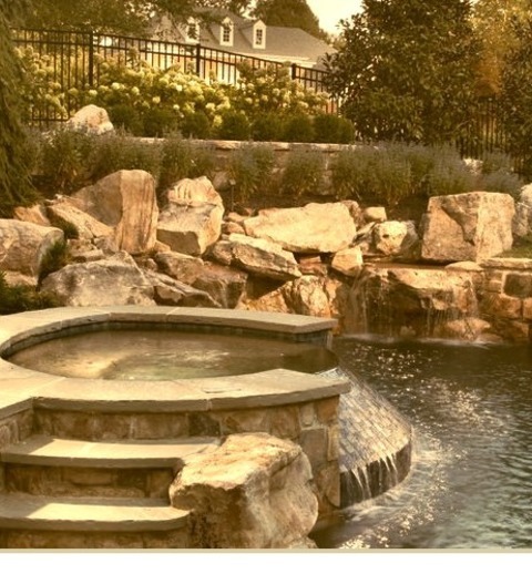 Example Of A Large Classic Backyard Stone And Custom-shaped Hot Tub Design