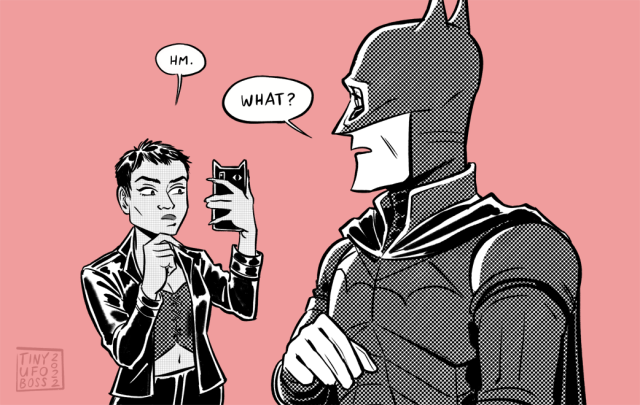 First panel of two panel comic: Catwoman (out of costume) is looking at her phone, while Batman stands nearby. She's saying, "Hm." as she holds up her phone to compare something on it to Batman. He's asking her, "What?"