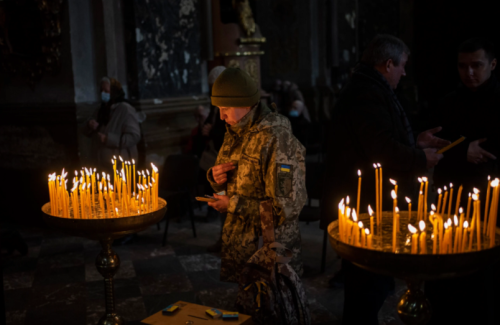 divinum-pacis: March 6, 2022: A Ukrainian woman dressed in military attire prays inside the Saints P