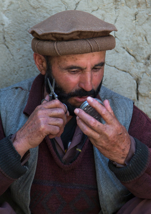 Afghan man cutting his beard in the street, Badakhshan province, Ishkashim, Afghanistan. Taken on Au