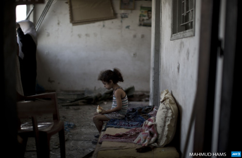 A Palestinian girl sits and eats in the rubble of her destroyed home, on August 2, 2014 following an