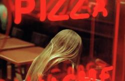 Constantine Manos, A young woman in a pizza parlor, Times Square, New York City, 2005 