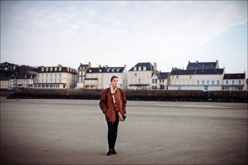 Kate walks at low tide on a beach at Arromanches-les-Bains, Basse-Normandie, France. April 2014.