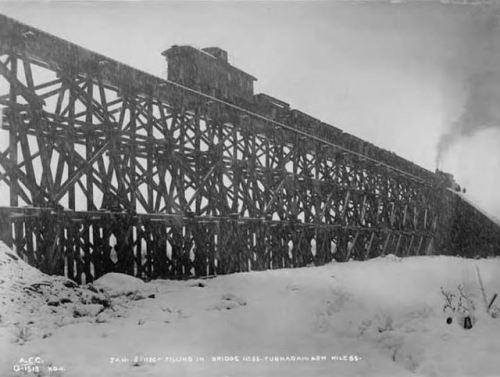 Alaska Railroad train on bridge at Mile 55 during snowfall, Alaska, 1920