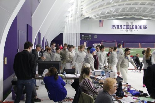 [ID: two photos of sabre fencers at an event. In the first photo, they’re clustered around a compute
