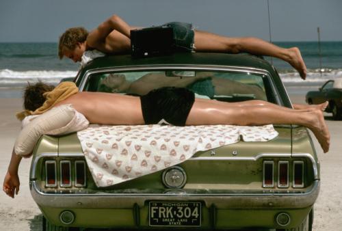 vintageeveryday:  Three young men sunbathe on a green Ford Mustang on Daytona Beach, 1973. 
