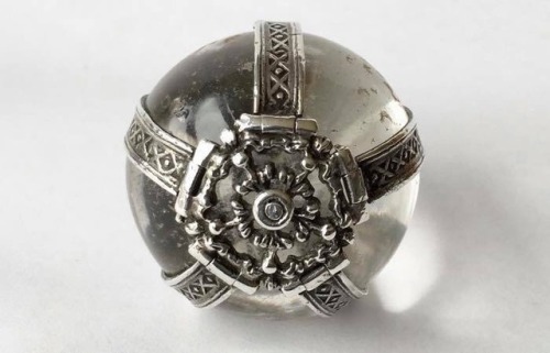 A rock crystal ball talisman mounted as a pendant in silver and decorated with stylised roses at eac