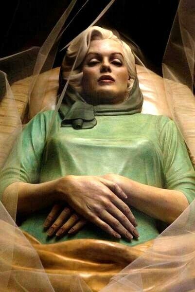 “At Rest”, by Italian artist Paolo Schmidlin, is a painted bronze  sculpture of Marilyn Monroe in her casket. The work presents the actress in the green dress and scarf she was buried in, complete with a veil covering her open coffin.