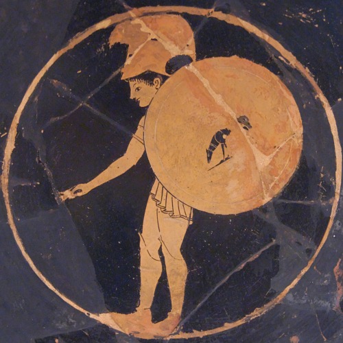 lionofchaeronea:A hoplite, carrying a shield with a dog as decoration.  Tondo of an Attic red-figure