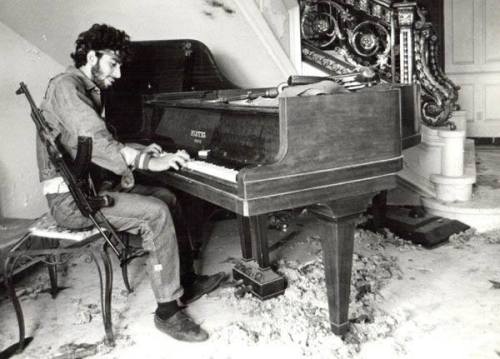 A Lebanese fighter plays the piano in a house his forces have recently taken over during the 1975-90