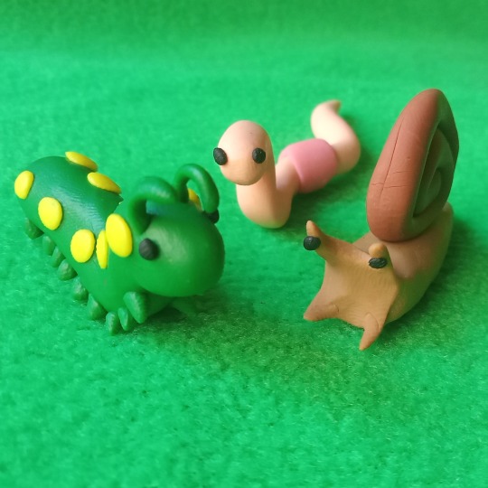 Three polymer clay bugs on a green fabric background
