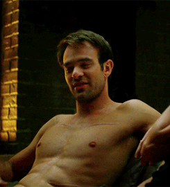 A shirtless Matt Murdock with his sinewy, muscular torso on view, smiling and talking to someone