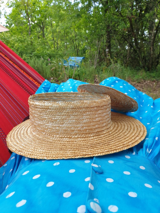 side view from flat crown and hat, held on a blue polkadot skirt from a red hammock 