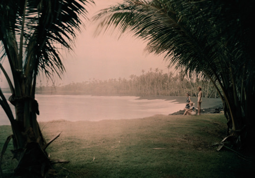 Young women look out on Kalapana Black Sand Beach in Hawaii. The beach gets its black color from vol