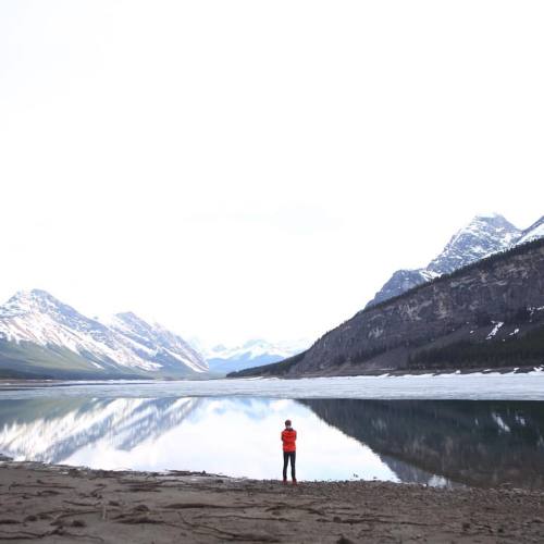 This is @scottcbakken standing by a beautiful lake wearing our new and improved red anorak jacket. I