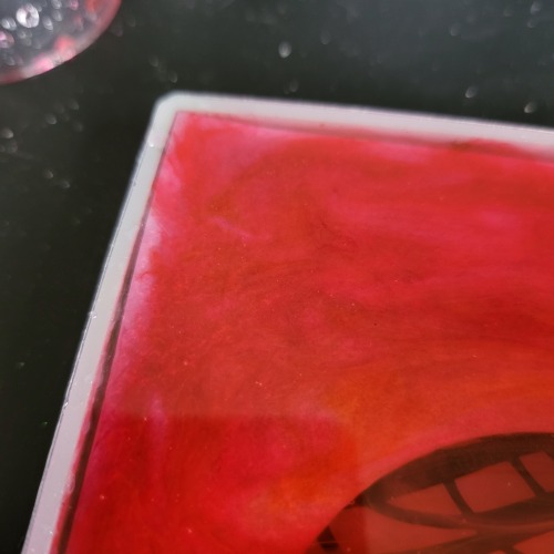 A close up view of the corner of the silicone mold and craft. The corner of the topmost paper layer can be seen lifted higher than the rest of the paper, creating a thin spot in the resin with thinner color as a result.