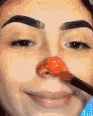 [Image ID: A Gif Of A Person Smiling While Putting On Clown Makeup With Brushes With A Final Cut To Their