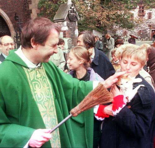 Polish priest blessing a cat during a mass house pet blessing. Kraków, 1995.