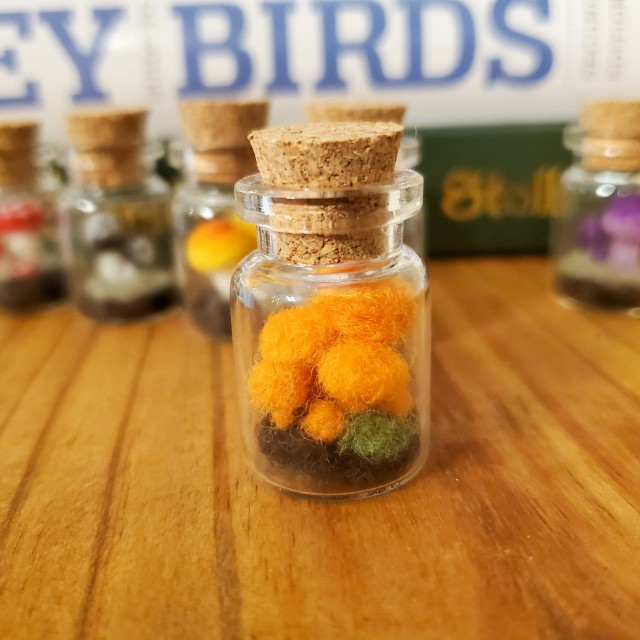 a photo of a jar containing a cluster of orange needle felted mushrooms 