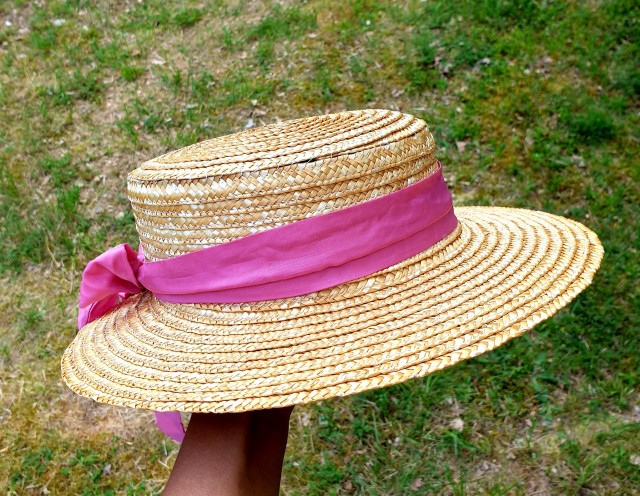 a straw hat with wide brim and a pink ribbon tied to it