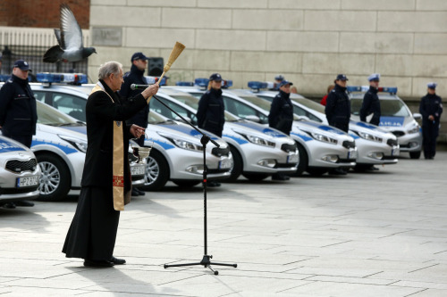 Polish priest blessing new police cars while under attack by a demon pidgeon. 2014, Warsaw.