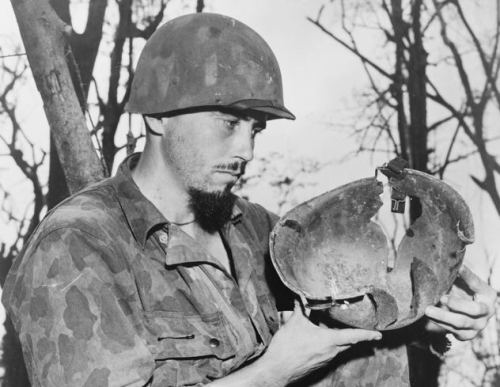 US Marine Ervin Bonow holding the helmet he was wearing when he was hit by a large piece of shrapnel