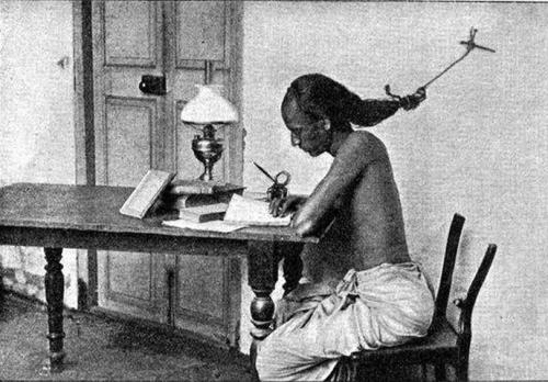 historicaltimes: A student at the University of Madras, India studying for exams with his hair tied 