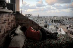 A boy sleeps amid the rubble of his destroyed