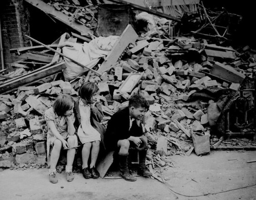 British children sit outside the remains of their home. London, England. September 1940.