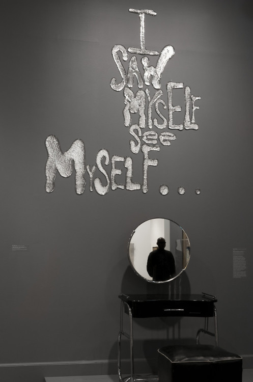 “Above the Art Deco vanity with mirror is I SAW MYSELF SEE MYSELF (2018), installed so the viewer li