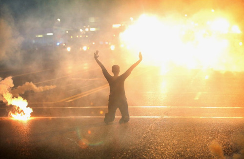 massconflict: A woman kneels on the street amid tear gas during a demonstration over the fatal shoot