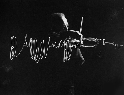 Jascha Heifetz playing violin in Mili’s darkened studio as light attached to his