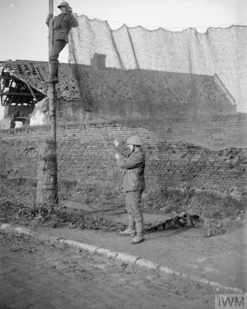 © IWM (Q 6462) Men of the 5th Battalion, Manchester Regiment hanging camouflage netting ac