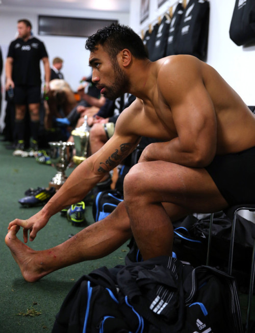 Rugby player stretching his feet and legs before putting socks and boots on for the game.