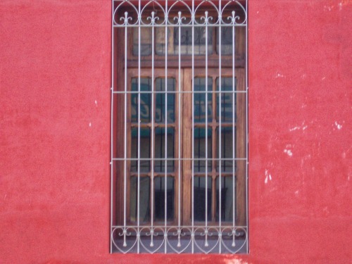 Ventana con una rejilla en una pared roja, Salta, Argentina, 2007.