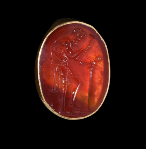gemma-antiqua:Ancient Roman gold ring with a carnelian intaglio depicting Vulcan creating a helmet, 