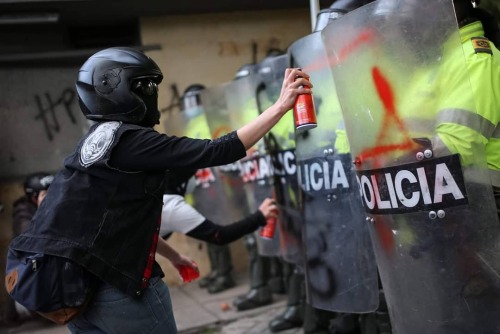 Protester in Colombia paints a riot cop&rsquo;s shield during the country-wide uprising following th