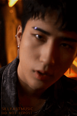 Harin lit by orange light sternly staring into the camera
