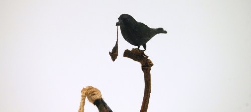 A crow dangling a poor mouse over a bubbling witches cauldron! There are a few snails crawling up th