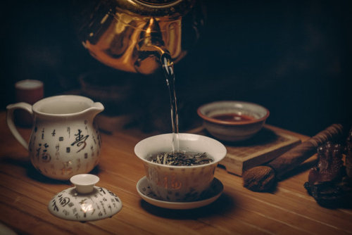 This photo shows a setup for brewing tea in a traditionally Chinese style, with water being poured f