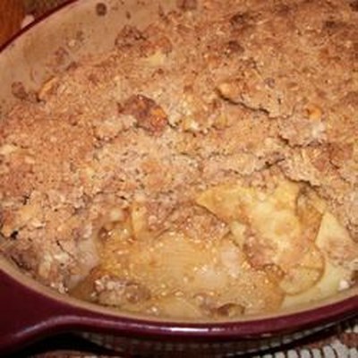 The sweet apple crisp is baked in a pie dish, with a buttery oat topping that includes coconut and w