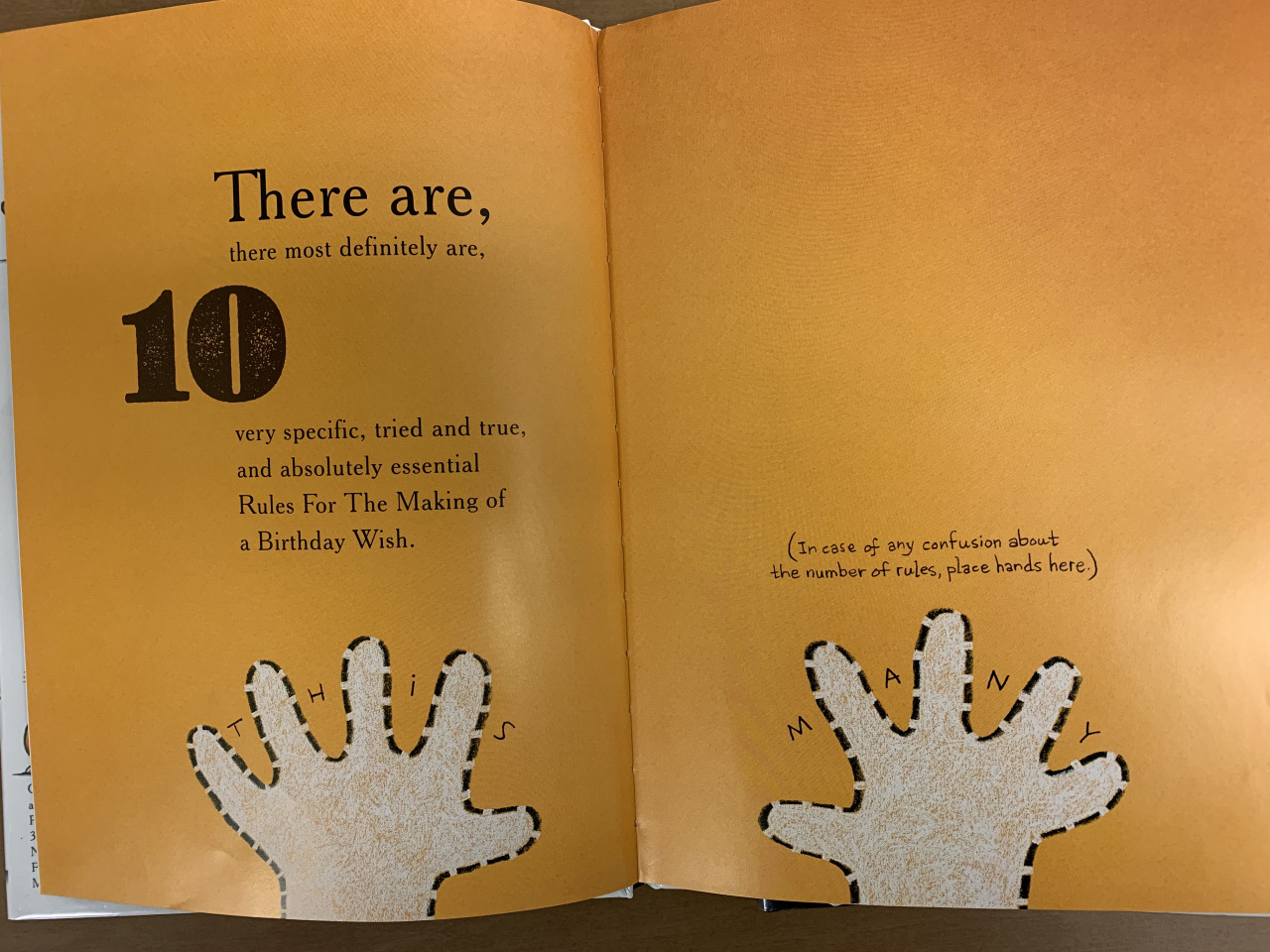 Interior pages of the book. There is a dotted line outline of two small hands at the bottom. The text reads There are, there most definitely are, ten very specific, tired and true, and absolutely essential Rules For the Making of a Birthday Wish. In case of any confusion about the number of rules place hands here. This many.