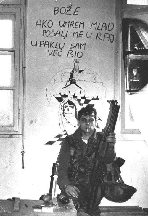 titovka-and-bergmutzen:  A Serb fighter poses in front of a wall mural that roughly translates to “G