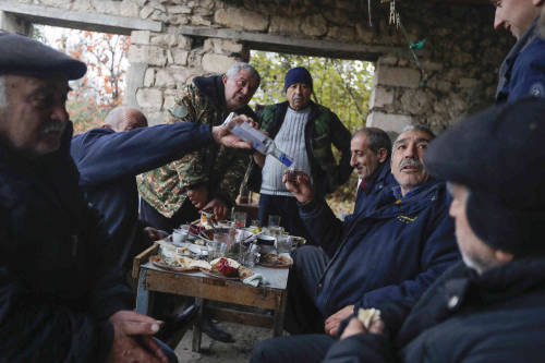 Ethnic Armenians drink vodka during their last dinner before leaving their homes in the village of M