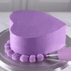 a purple heart cake rotating and frosting being piped along the base