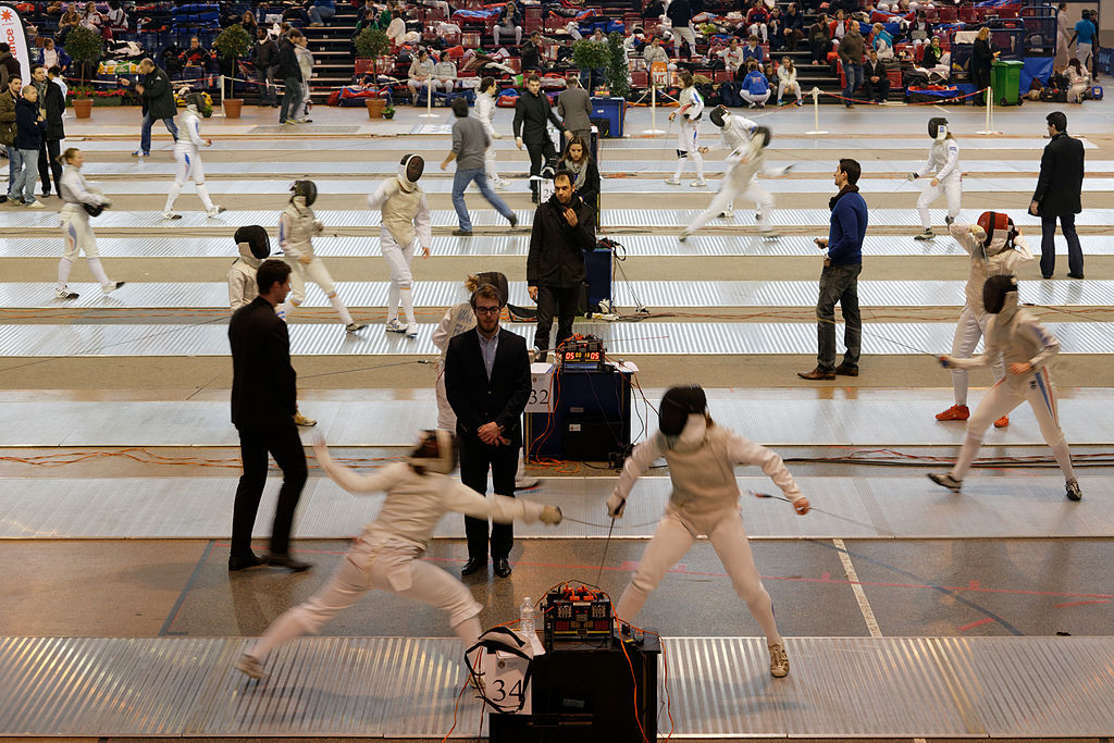 modernfencing:[ID: a view of a fencing competition, with eight foil bouts going on
