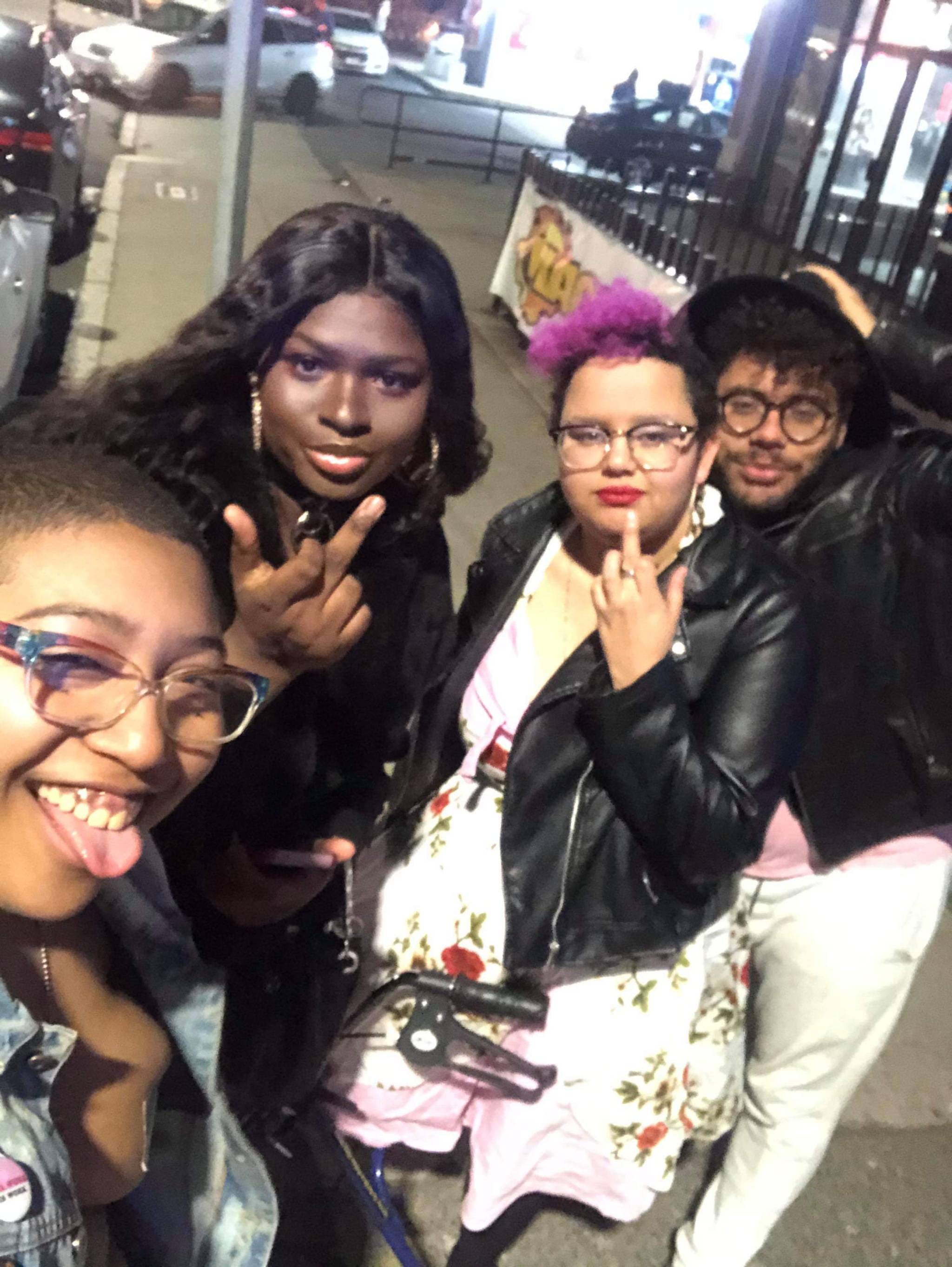 ::help a black trans family live!![image description: 4 black people are posing for a picture. pictured from left: a black androgynous nonbinary person (@juicyparsons ) is wearing a denim vest and duct tape on his chest, and is smiling at the camera,