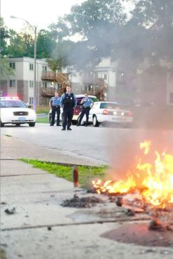 bossladykara:  thetpr:thesylverlining:defend-p0ptarts:  Here’s a picture of cops watching the Mike Brown memorial burn.  Put this everywhere. Show everyone. The protest pictures capture the determination and strength of the people they abuse. Even if