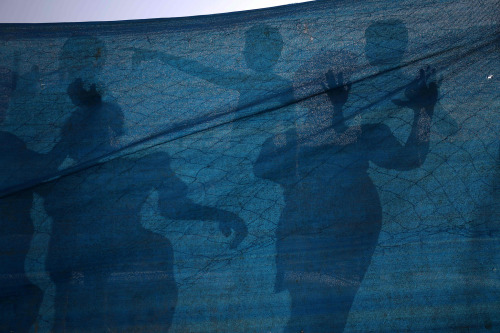 fotojournalismus:The shadows of Palestinians are seen on a piece of gauze as they cool down at a poo